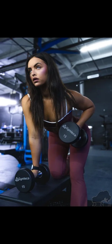 Taylor demonstrating a dumbbell row in the gym